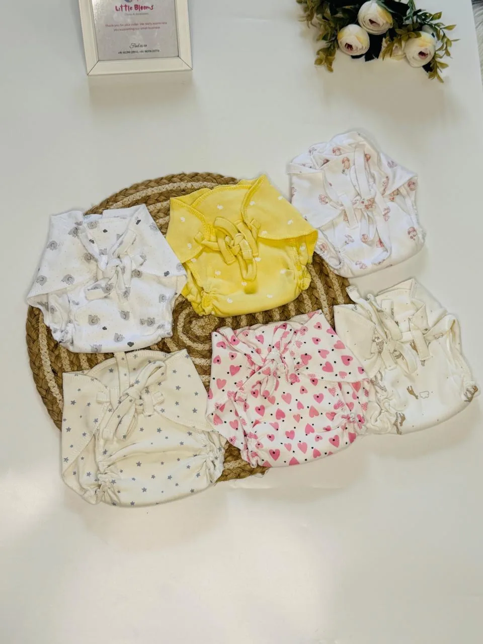 Newborn outfits and cloth diapers folded into a woven basket