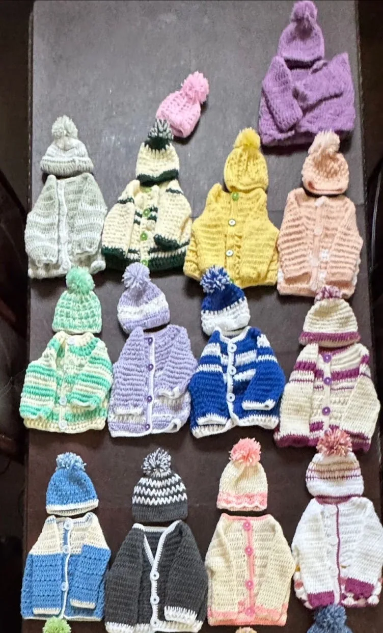 Rows of hand-crocheted baby sweaters and hats in pastel colours